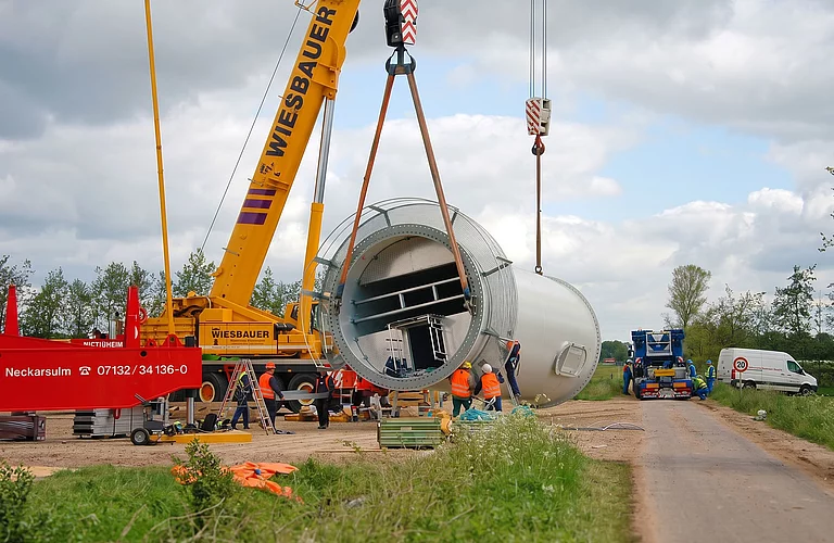 Montage eines großen technischen Anlagenbehälters mit Mobilkran auf einer Baustelle